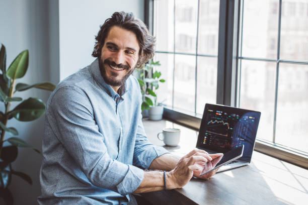 Businessman working from home office Businessman working from home. Using laptops. Trading stock or cryptocurrencies. Trading app on screen. market stock pictures, royalty-free photos & images