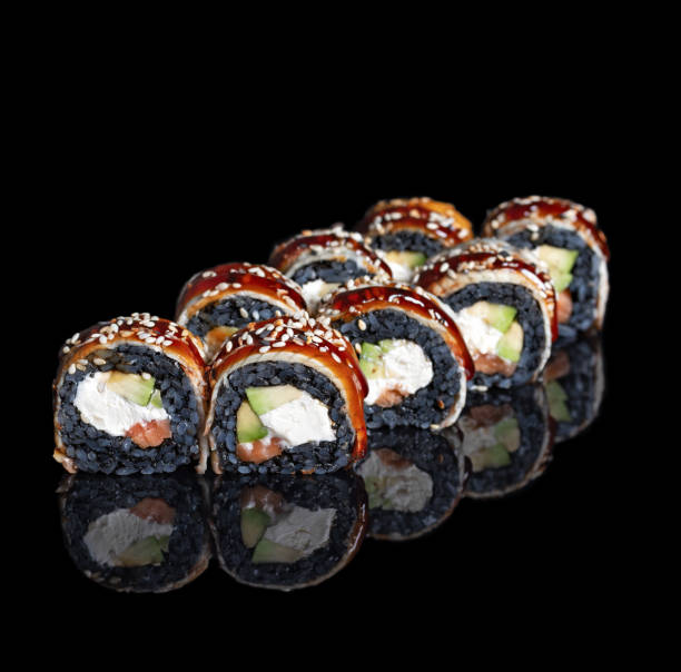 istock Black dragon sushi roll. Sushi Rolls with black rice, Salmon, Avocado with reflection on black background. 1320689396