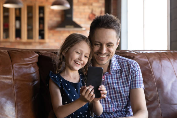 istock Happy daddy and daughter kid watching content on mobile phone 1320693221
