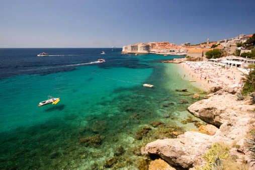 Tourists and locals chill on the city beach near the ancient walls of Dubrovnik in south Dalmatia