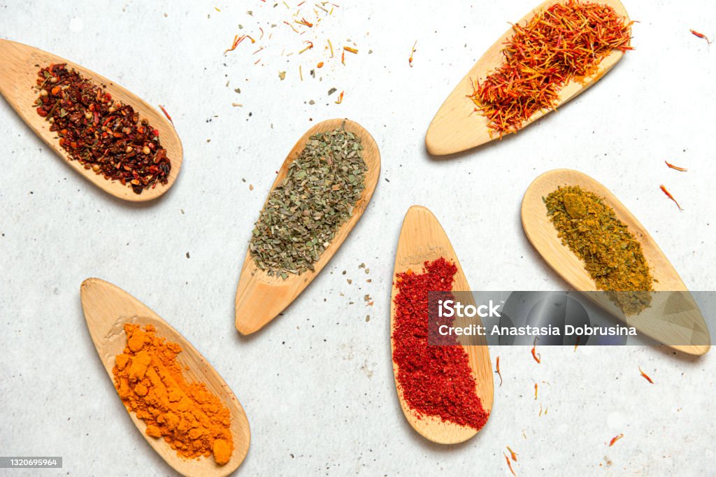 Variates of spices on concrete table. Food concept background. Chili, paprika, saffron, shambhala, turmeric on wooden plates. Colorful background from various herbs and spices for cooking Culture of India Stock Photo