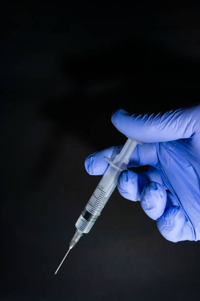 istock Male nurse using syringe on black background 1320699968