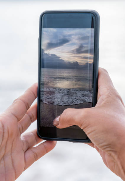 istock Female hands holding a smartphone on the beach 1320700085