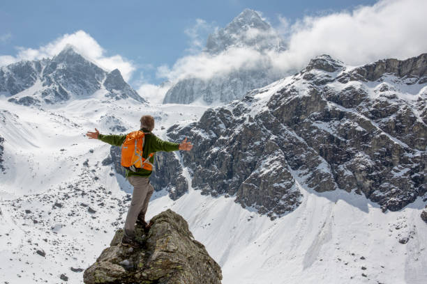 istock Hiker stands on mountain peak with arms outstretched 1320709866