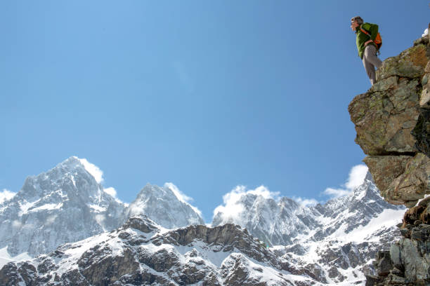 istock Hiker stands on edge of mountain cliff 1320709901