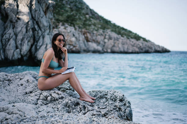 Young woman writes in her journal on Mediterranean beach