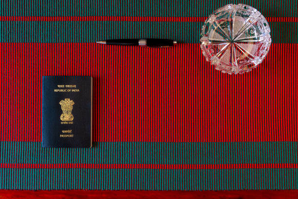 flat lay of the new india passport colocado en una tela tejida de rojo y verde que hace alusión a la navidad. en la mitad superior es un bolígrafo y un cenicero de cristal - passport blank book cover empty fotografías e imágenes de stock