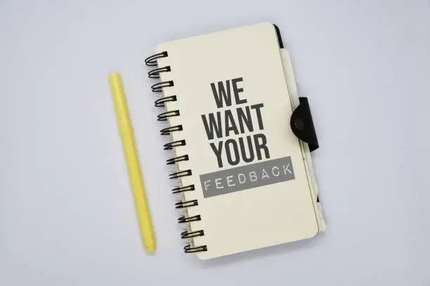 Photo of 'We want your feedback' word on the notebook.