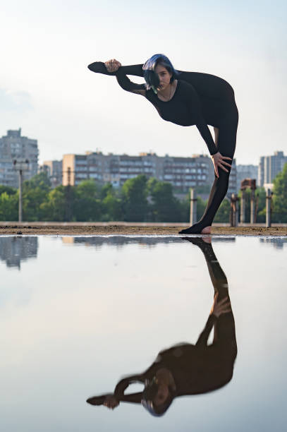 柔軟でフィット感のある女の子は、分割で1フィンにバランスを保ちます。ヨガ、コントロール、健康的なライフスタイルのコンセプト - yoga city handstand control ストックフォトと画像