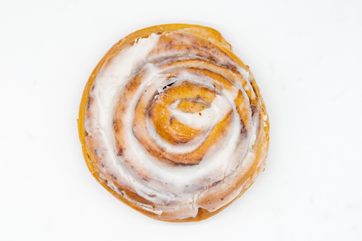 An overhead view of a delicious homemade cinnamon roll with a spiral on a white background