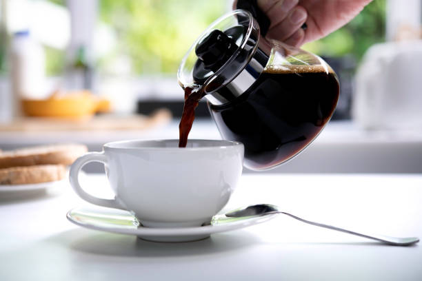 istock A hand pouring steaming coffee in to a cup on table in the kitchen 1320728208