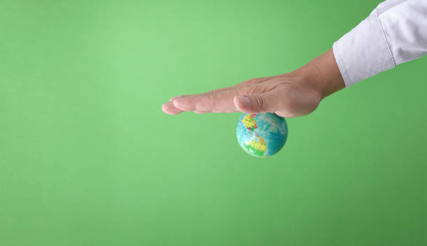 geschäftsmann mit dem globus an seiner handfläche festgeklebt, grüner hintergrund. - crushed human hand earth ball stock-fotos und bilder