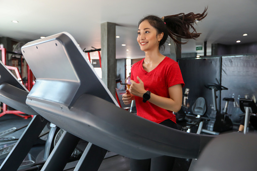 Asian women running sport shoes at the gym while a young  woman is having jogging on the treadmill