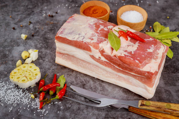 istock Boneless raw pork belly with garlic on dark background. 1320735371
