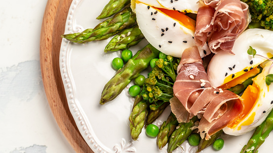 Eggs Benedict Poached eggs with prosciutto, asparagus, Healthy food, ketogenic diet, diet lunch concept. Keto Paleo diet menu, top view.