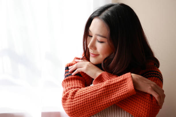 close up portrait of a young beautiful Asian woman wearing a sweater at home. She felt relaxed in the room with the morning sunny. stock photo
