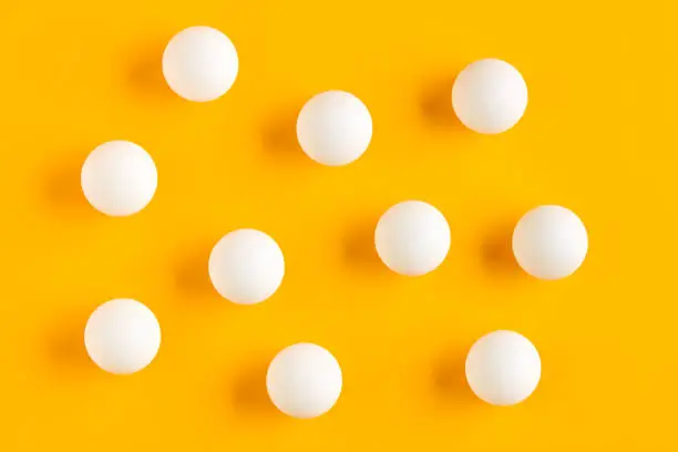 Photo of White table tennis balls on yellow background.