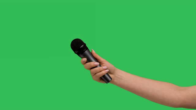 Захват микрофона. Зелёный микрофон интервью. Пульт на зеленом фоне. Рука держит микрофон женская на зелёном фоне. Куртка захвата микрофона.