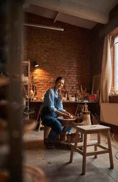 istock Young Caucasian ceramicist shaping clay pot in pottery workshop 1320746912