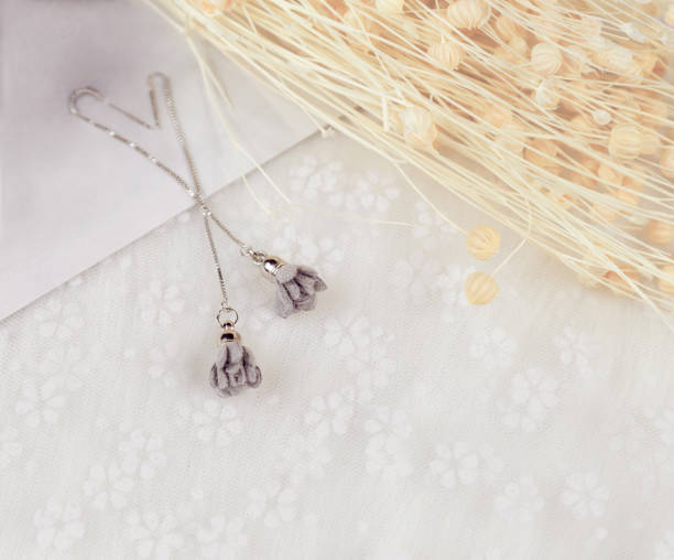 istock Grey pendant earrings, its shape is a flower.There are decorative objects such as cardboard and bouquet specimens beside the earrings. These items are placed on the tulle. Earrings look very elegant and fashionable. 1320746989