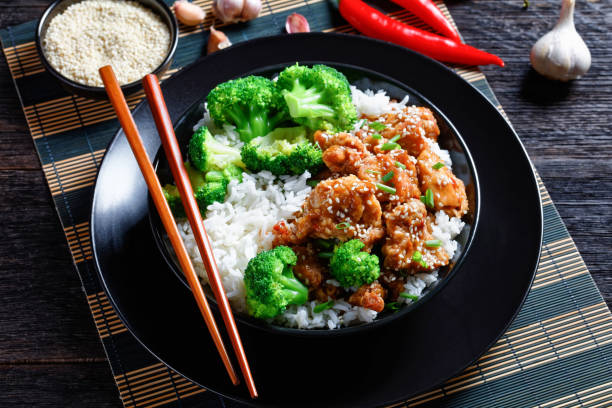 general tso"u2019s chicken crispy chinese chicken bites in a black bowl with rice and steamed broccoli florets, horizontal view from above - chicken general tso food imagens e fotografias de stock