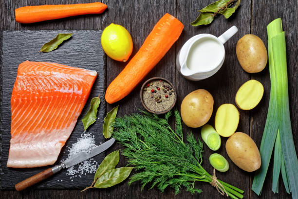 pezzo di salmone crudo su una tavola di pietra, crema, patate, carote, porro e aneto su un tavolo di legno rustico, vista orizzontale dall'alto, posa piatta - stone leek foto e immagini stock