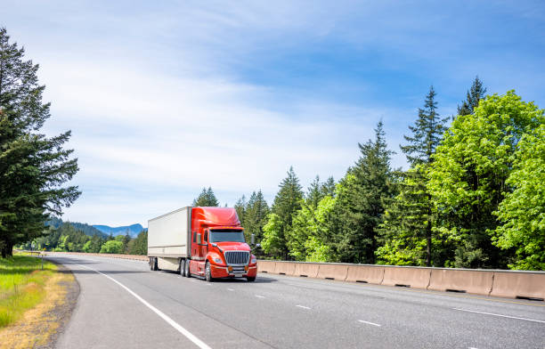 녹색 여름 나무와 분할 된 고속도로 도로에서 이동 건조 밴 세미 트레일러에서화물을 수송 하는 에너지 절약 디자인 큰 장비 레드 세미 트럭 - semi truck truck highway red 뉴스 사진 이미지