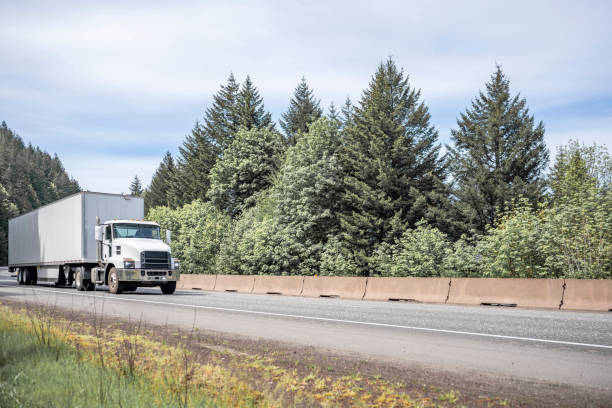 istock Powerful white day cab big rig semi truck transporting cargo in dry van semi trailer running on the highway road for local delivery 1320749450