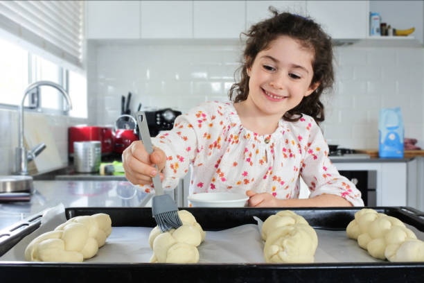 Happy Jewish girl baking sweet Challah bread for Sabbath Jewish Holiday Happy young Jewish girl (female age 7) baking sweet Challah bread for Sabbath Jewish Holiday in home kitchen. jewish sabbath photos stock pictures, royalty-free photos & images