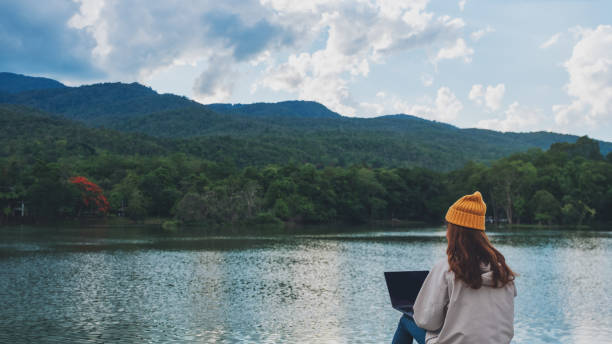 istock a young woman using and working on laptop computer while traveling mountains and lake 1320755559