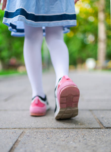 小さな女の子は道路のクローズアップで歩く - children only healthy lifestyle vertical close up ストックフォトと画像