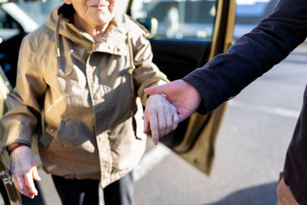 Asian senior and nursing care staff Japanese nursing care staff supports Japanese senior woman getting off a car. nervous holding hands stock pictures, royalty-free photos & images