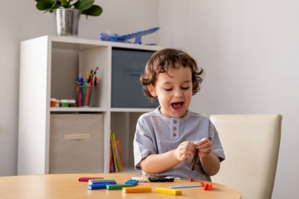 istock Happy little boy sculpts from plasticine while sitting at the table. 1320755788