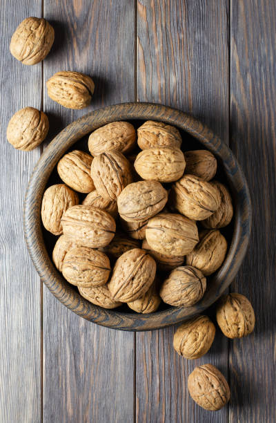 istock Walnuts in a plate on a brown wooden background. Nuts are a source of vegetable protein. Flat top view 1320757825