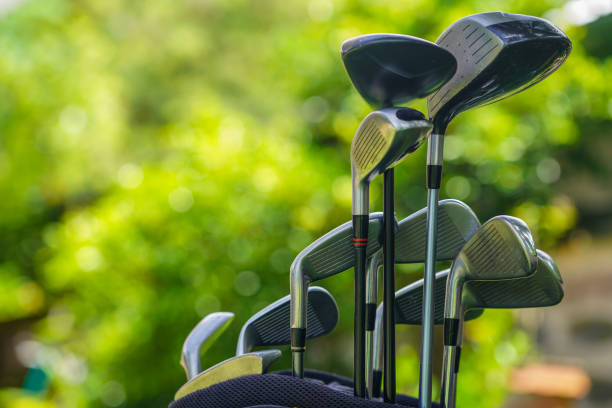 Golf bag and clubs in front of a blurred golf course background,