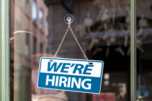 We're hiring sign Close-up on a blue and white sign in a window with written in "We're hiring". hiring stock pictures, royalty-free photos & images