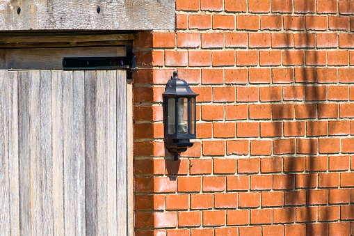 Electric light on the side of a house against a red brick wall in england