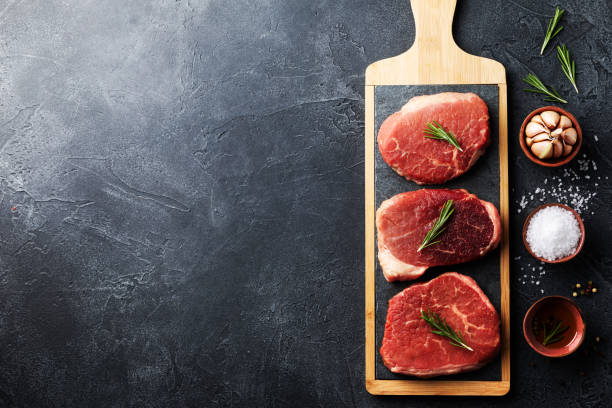 istock Raw beef meat on kitchen board. Top view flat lay with copy space. 1320773284