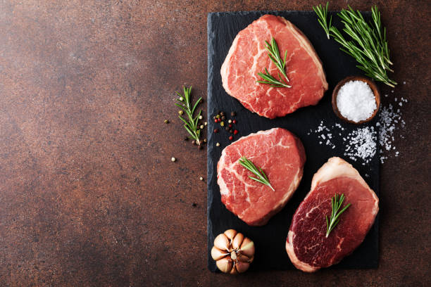 istock Raw fresh beef meat on slate black plate. Top view flat lay with copy space. 1320773322