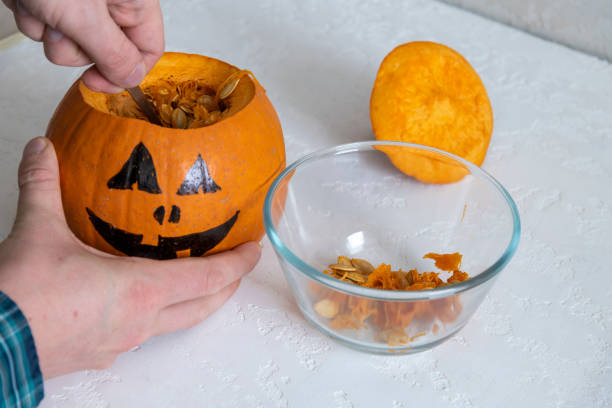 istock Person removes seeds from Halloween pumpkin 1320777573