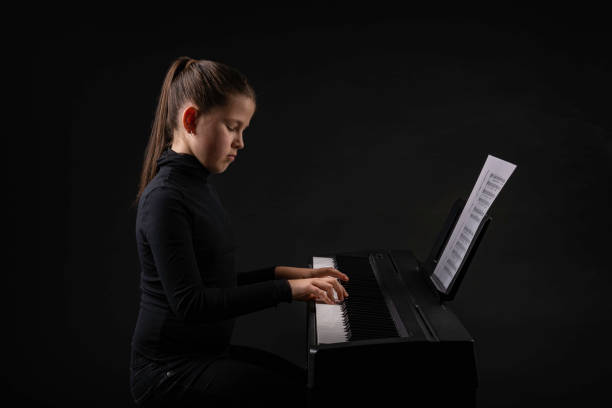 彼女の前にノートを持ってピアノを練習慎重な若い女の子。楽器の概念を学ぶ。 - piano keyboard instrument one person piano key ストックフォトと画像