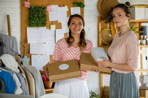 istock Two businesswomen smiling at camera while holding packages 1320782833