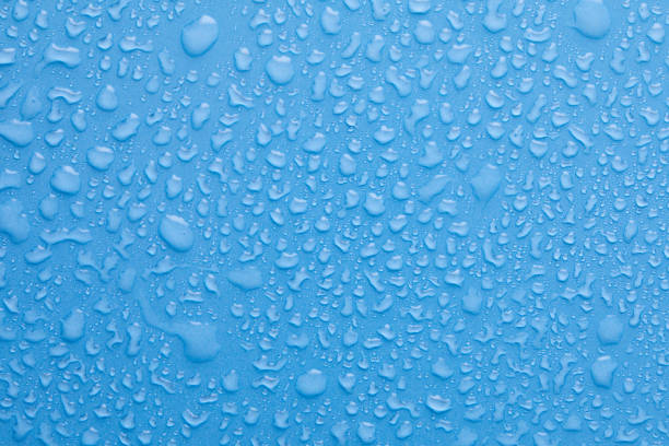 istock Water drops on blue background. Drops of water on surface. Macro photo. Splash pattern. 1320786680