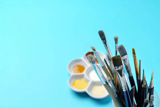 Photo of Color paints and brushes on paper background