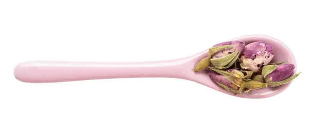top view of old dried rosebuds in ceramic spoon isolated on white background