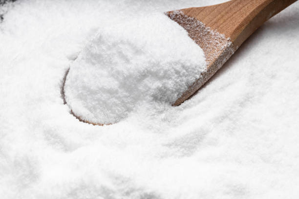 wooden spoon with dextrose sugar close up on pile stock photo