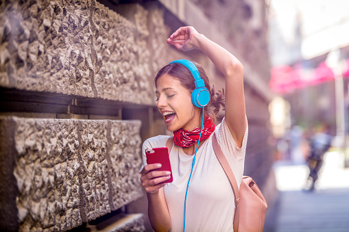Funny girl listening to the music with earphones from a smart phone