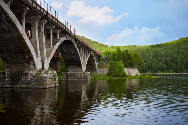 istock Old arch bridge over the river on a summer day. 1320789971