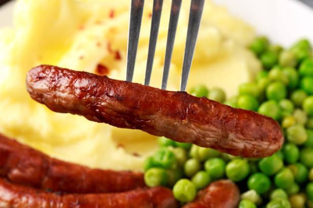 schweinefleisch chipolata würstchen mit hausgemachten kartoffelpüree und grünen erbsen - weenies stock-fotos und bilder