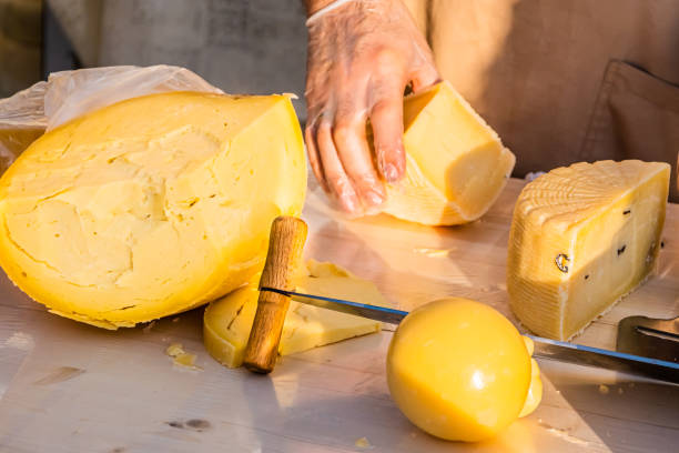 istock Shopkeeper's hands cutting a head of cheese 1320793704